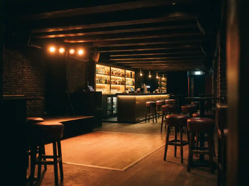 Verlicht podium in een intiem Amsterdams nachtclub interieur met amberkleurig licht, bakstenen muren en een verlichte bar op de achtergrond.